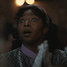 a woman wearing white gloves and a purple shirt is making a surprised face