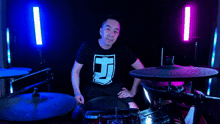 a man wearing a black shirt with the letter b on it is playing drums
