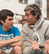two young men are sitting next to each other and one of them has a shirt that says ' ao ' on it