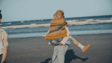 a person carrying a child on their shoulders on the beach