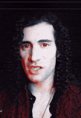 a man with curly hair has red eyes and a red shirt