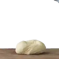 a person kneading a ball of dough on a table