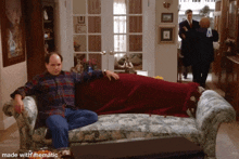 a man sits on a couch in a living room with the words made with mematic on the bottom right