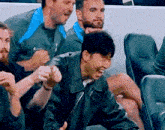 a man wearing a leather jacket is laughing while sitting in a stadium