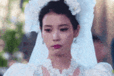 a woman in a white wedding dress and veil looks sad