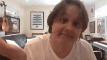 a woman in a white shirt looks at the camera with a poster on the wall that says lloyd cooper