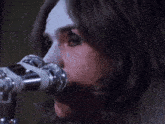 a woman singing into a microphone with a white face paint