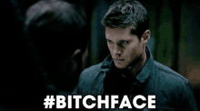 a man in a black jacket is standing next to another man with the words #bitchface above him