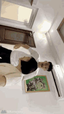 a man and a woman are dancing in a room with a painting on the wall and the word momento on the bottom
