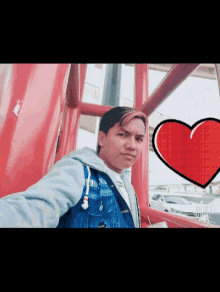a man is taking a selfie with a red heart in the background