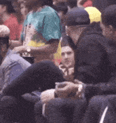 a man wearing a tie dye shirt sits in the stands with other people