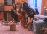 a group of women are dancing in a living room with a couch