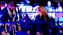 a man and woman are standing next to each other in a wrestling ring .