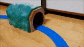 a toy train is going through a green tunnel on a wooden floor .