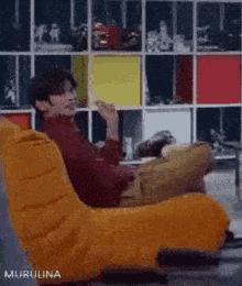 a man is sitting in a yellow chair with his legs crossed and smoking a cigarette .