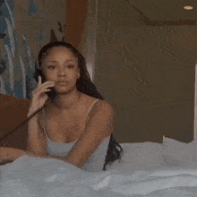 a woman is sitting in bed talking on a telephone .