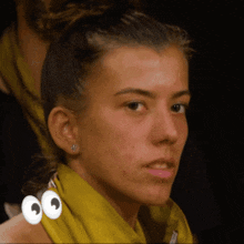 a woman with a yellow scarf around her neck has googly eyes on her face