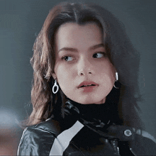 a woman wearing hoop earrings and a black leather jacket