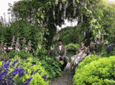 a man and a woman are sitting in a garden surrounded by flowers