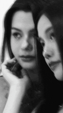 a black and white photo of a woman looking at herself in the mirror
