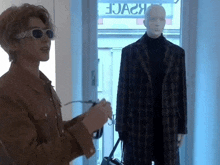 a man wearing sunglasses is standing next to a mannequin in a store .