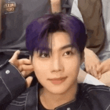 a close up of a person with purple hair holding a cell phone .