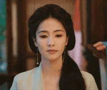 a close up of a woman 's face with a ponytail and earrings
