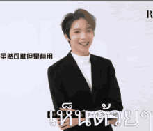 a man in a suit is smiling in front of a sign that says ' r '