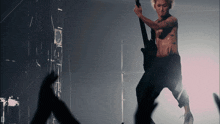 a shirtless man is playing a guitar in a dark room