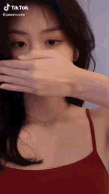 a woman in a red tank top covering her face with her hand and a tiktok watermark