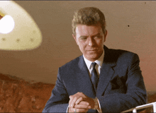 a man in a suit and tie has his hands folded in front of him