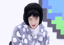 a boy wearing a black knitted hat and ear muffs looks down with his eyes closed