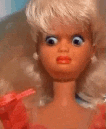 a close up of a barbie doll wearing a pink dress and earrings .