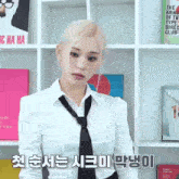 a woman wearing a white shirt and black tie is standing in front of a bookshelf with foreign writing on it