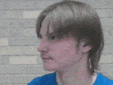 a close up of a man 's face with a blue shirt on