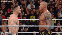 two wrestlers are facing each other in a ring with a crowd behind them