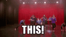 a group of people are dancing on a stage with the words this written on the floor .
