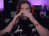 a man wearing headphones and a black shirt is covering his face .