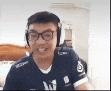 a man wearing headphones and a blue shirt with the letter w on it smiles