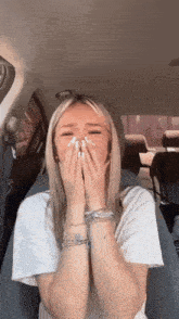 a woman in a white shirt is covering her face with her hands
