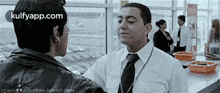 a man in a white shirt and tie is talking to another man in a black jacket .