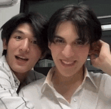 a couple of young men are standing next to each other and smiling .