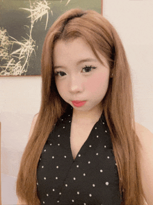 a girl with long blonde hair wearing a black polka dot top