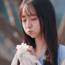 a girl with long hair is blowing a kiss while holding a piece of paper