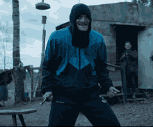 a man in a blue and black jacket holds a gun in his right hand and the word columbia is on his left