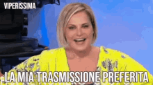a woman in a yellow shirt is smiling with the words " la mia trasmissione preferita " above her