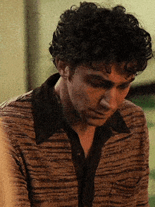 a close up of a man with curly hair wearing a striped shirt .