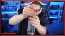 a man is holding a bottle of water in front of a computer screen .