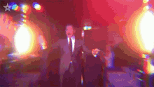 a man in a suit and tie is dancing in front of a star