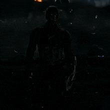 a man in a captain america costume holds a shield in the dark